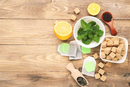 Foto de Bolsas de té con hojas de menta, limón y terrones de azúcar sobre mesa de madera marrón - Imagen libre de derechos