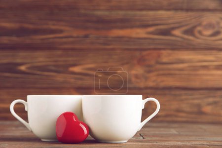 Foto de Tazas blancas y corazón rojo sobre fondo de madera marrón - Imagen libre de derechos