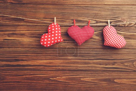 Photo for Fabric hearts hanging on rope on brown wooden background - Royalty Free Image