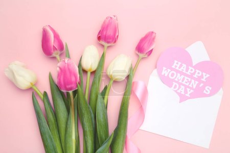Blumenstrauß aus Tulpen und Umschlag mit Karte mit Text Happy Women 's Day auf rosa Hintergrund