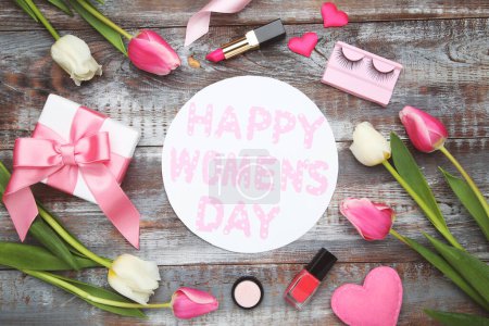 Foto de Flores de tulipanes, corazones, cosméticos, caja de regalo y tarjeta redonda con texto Feliz Día de la Mujer sobre fondo de madera - Imagen libre de derechos