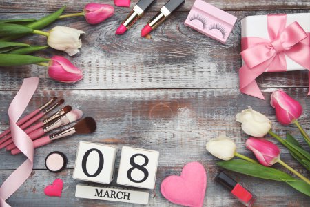 Photo for Flowers of tulips, cube calendar, cosmetics, makeup brushes and hearts, gift box, space for text on wooden background - Royalty Free Image