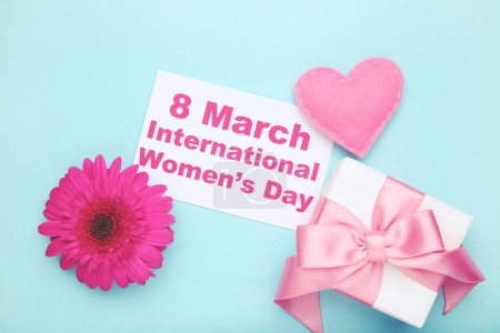 Téléchargez les photos : Gerbera fleur, feutre coeur, boîte cadeau et carte avec texte 8 Mars Journée internationale de la femme sur fond bleu - en image libre de droit