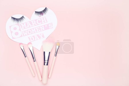 Photo for Card in shape of heart with text 8 March Women's Day and set makeup brushes on pink background - Royalty Free Image