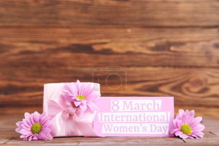 Foto de Flowers of chrysanthemums, gift and card with text 8 march International Women's Day on brown wooden background - Imagen libre de derechos