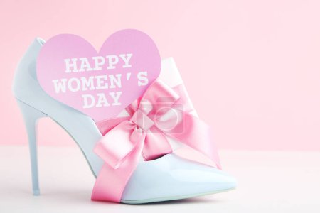 Téléchargez les photos : Gift box, card in shape of heart with text Happy Women's Day and blue high-heeled shoe on pink background - en image libre de droit