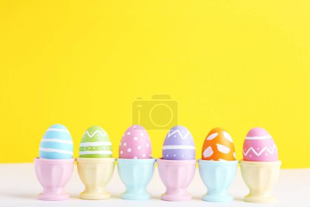 Téléchargez les photos : Rangée oeufs de Pâques colorés dans des peuplements sur fond jaune - en image libre de droit