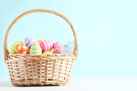 Foto de Huevos coloridos de Pascua en cesta sobre fondo azul - Imagen libre de derechos