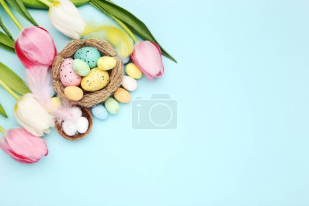 Téléchargez les photos : Eggs in nests and flowers of tulips on blue background - en image libre de droit