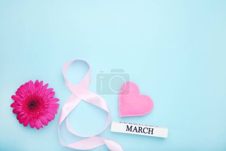Photo for Pink gerbera flower, felt heart and ribbon in shape of figure number 8 on blue background - Royalty Free Image