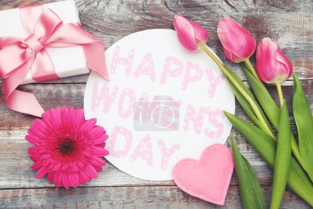 Téléchargez les photos : Gerbera and tulips flowers, felt heart, gift box and roundcard with text 8 Happy Women's Day on wooden background - en image libre de droit