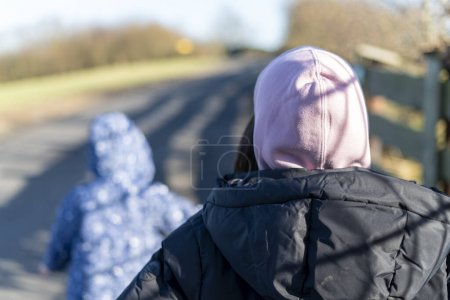 Rear view of two girls in winter clothes walking on the road