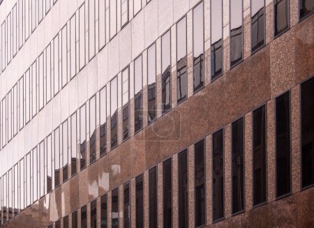 Close up of a modern office building with glass windows and reflections.