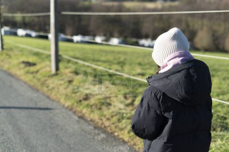 Young woman walking on a country road in winter. Rear view.