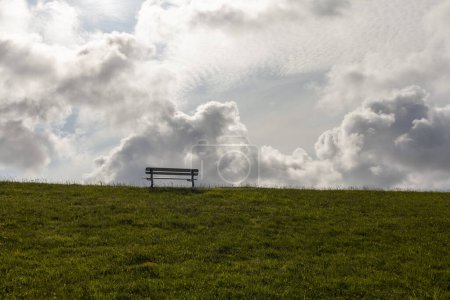 Téléchargez les photos : Banc sur une prairie avec herbe verte et nuages en arrière-plan - en image libre de droit