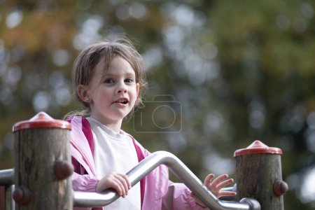 Portrait of a cute little girl playing on the playground in autumn