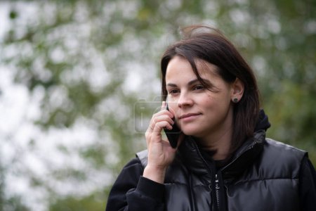 Retrato de una joven hablando por teléfono en el parque