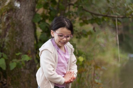 Little girl wearing glasses in the park with a tree in the background