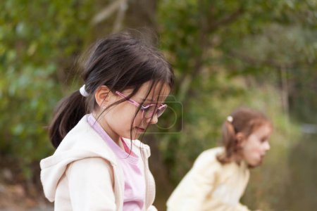 Cute little girl playing with her sister in the park, shallow depth of field
