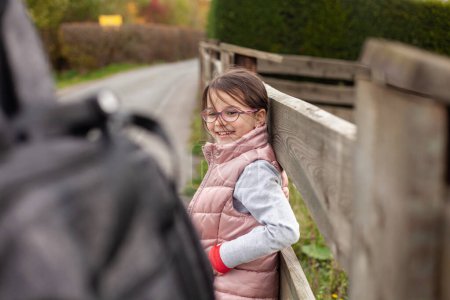 Petite fille mignonne avec des lunettes et un sac à dos sur une route de campagne