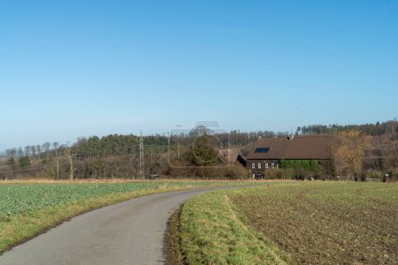 Paisaje rural con una carretera rural y una granja en el fondo