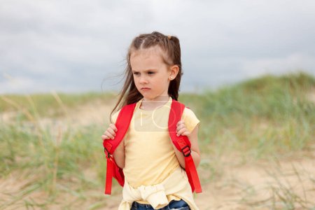 Portrait of a cute little girl with backpack on the beach.