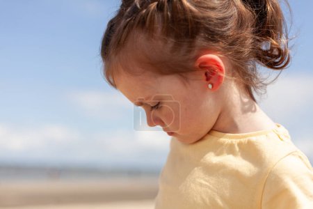 Portrait of a little girl on the beach looking at the sea