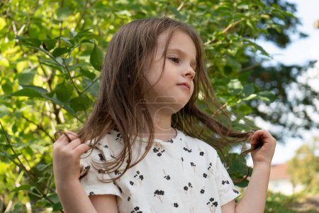 Portrait of a little girl with long hair in the park.