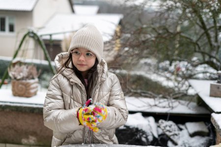 Cute little girl playing with ice in the winter garden. Winter fun.