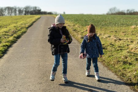 Two little girls walking on a country road in the countryside in winter