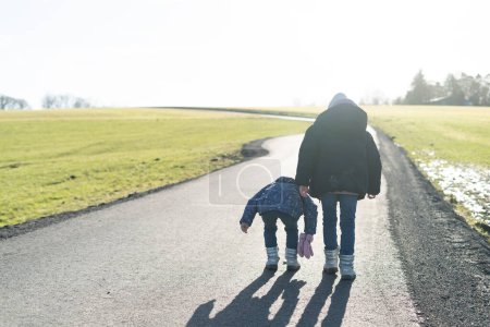 Madre e hija caminando por un camino rural en primavera.