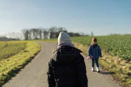 Two little girls walking on a country road in the countryside in winter
