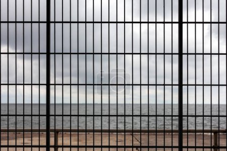 View of the sea through the bars of a restaurant in Spain.