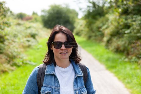 Portrait of a beautiful young woman wearing sunglasses on a country road