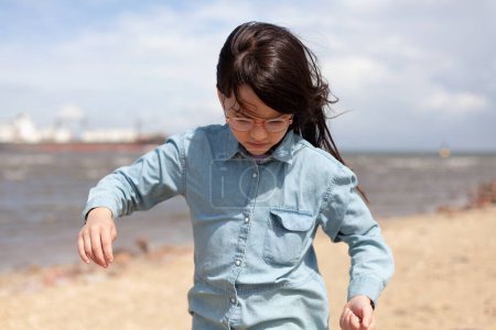 Little girl playing on the beach by the sea in the summertime