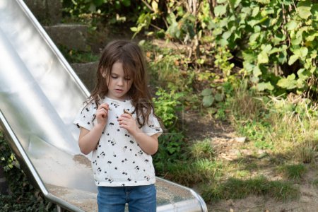 Porträt eines schönen kleinen Mädchens, das auf einer Rutsche im Park spielt