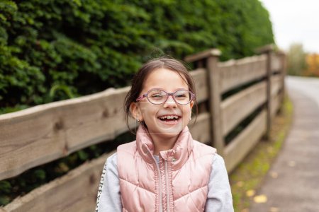 Portrait of a cute little girl in a pink jacket and glasses