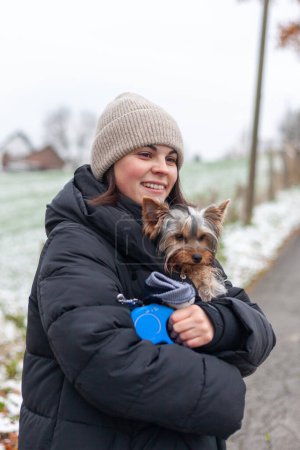 Junge Frau mit Yorkshire-Terrier-Hund im Winterpark.