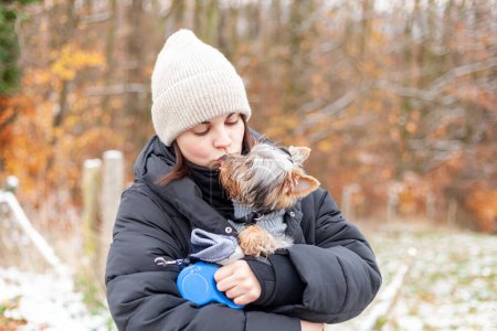 Young woman with yorkshire terrier dog in the park in winter