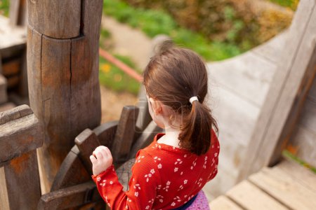 little girl in a red T-shirt plays on the playground on a pirate ship