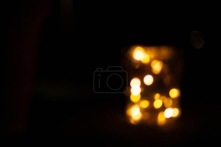 Glas mit Lichtern auf dunklem Hintergrund in der Nacht