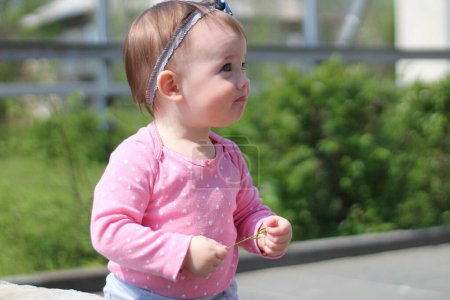 A little girl in a pink jacket walks down the street