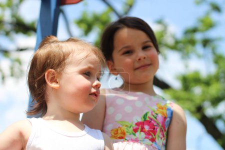 El espíritu alegre y despreocupado de dos niñas disfrutando de su tiempo juntas en el patio de recreo durante un día soleado de verano.