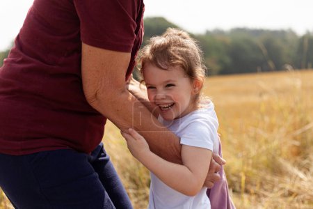 the beautiful connection between a little girl and her grandmother in the midst of nature, celebrating joy, love, and togetherness against the backdrop of a golden wheat field