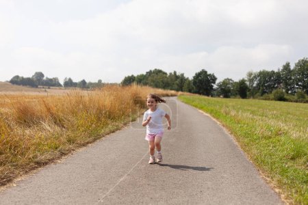 Little girl happily running along a quiet rural road, surrounded by the beauty and tranquility of the countryside