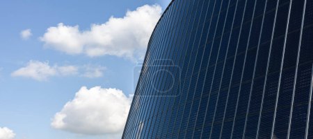 Panoramic view of modern office building against blue sky with clouds