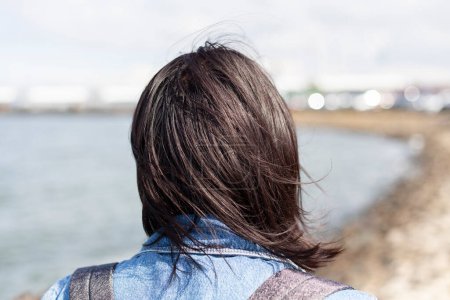 Rückansicht eines Mädchens mit langen Haaren auf dem Hintergrund des Meeres