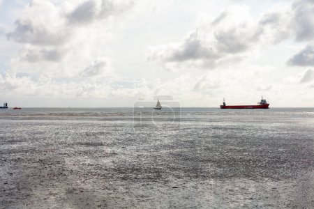 Seascape with cargo ship in the sea and cloudy sky.