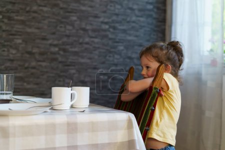 Linda niña sentada en la mesa en un café y tomando café