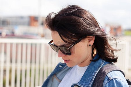 Portrait of a beautiful young woman in jeans jacket and sunglasses.